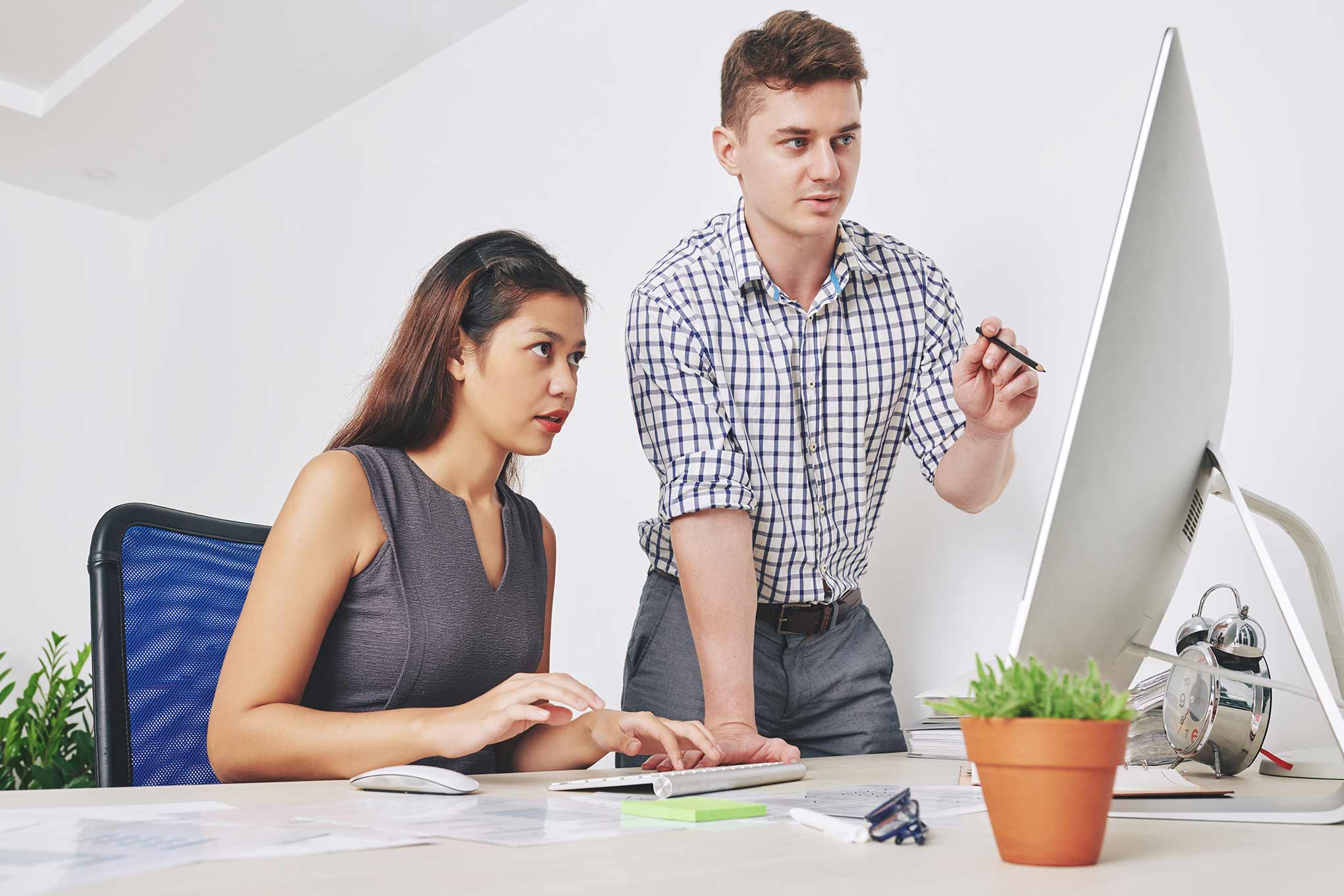 Woman working on a computer with a man helping her.