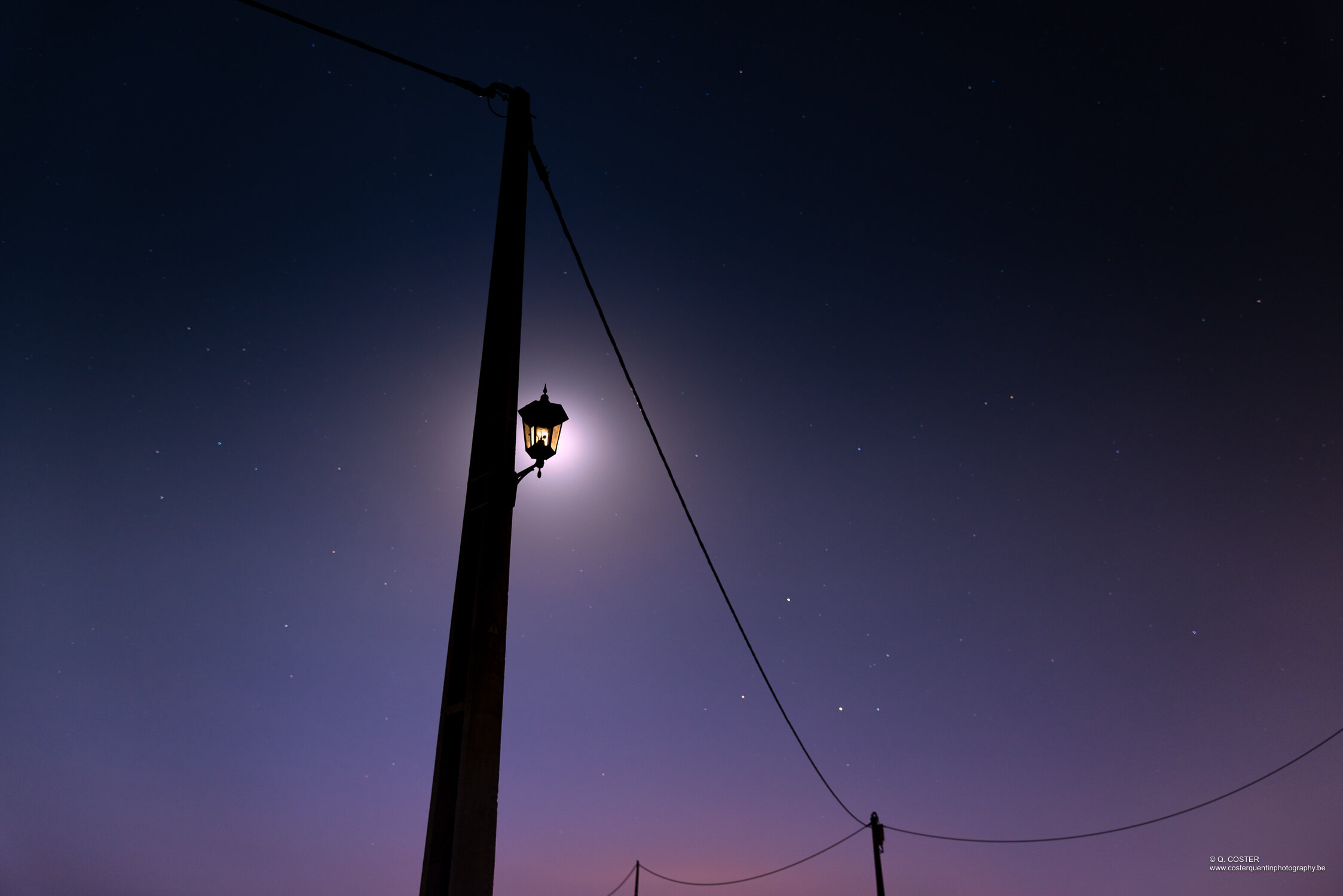 
        The moon lights up a street light